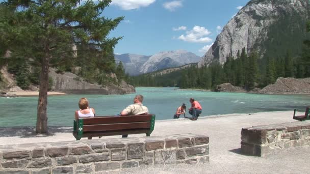 Des gens assis sur un banc à la rivière Bow — Video