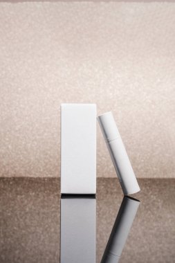 Beyaz kozmetik tüp ve altın yaldızlı arka planda bir kutu. Güzellik reklamı konsepti, blog, geometrik minimalizm ürün fotoğrafçılık, model, kopyalanma alanı, yansıma