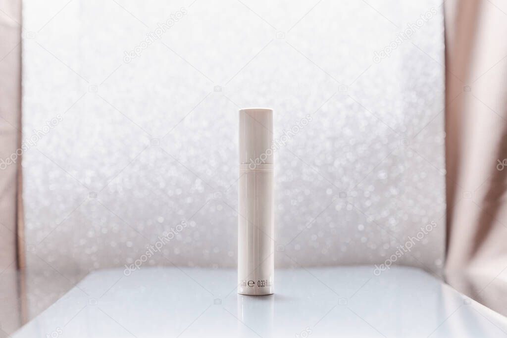 White cosmetic tube on silver glitter background. Beauty ad concept, blog, geometrical minimalism product photography, mockup, copyspace