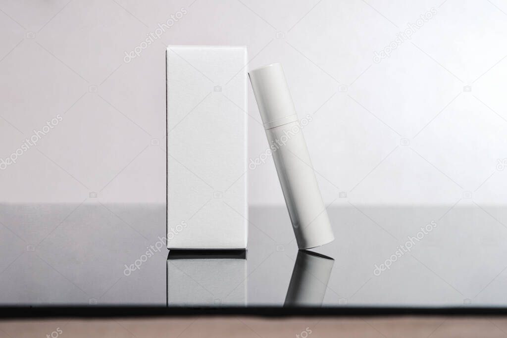 White cosmetic tube and box on white background. Beauty ad concept, blog, geometrical minimalism product photography, mockup, copyspace