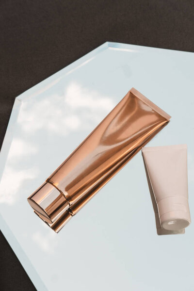 Два белых и золотых косметических трубки на зеркальном фоне, косметический продукт, макет упаковки брендинга, минимализм, вид сверху