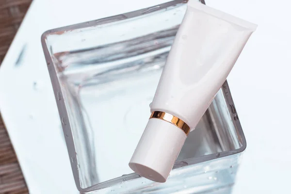 白色的化妆品筒在一个碗里 水与白色背景 美容产品 品牌包装模型 顶部视图 — 图库照片