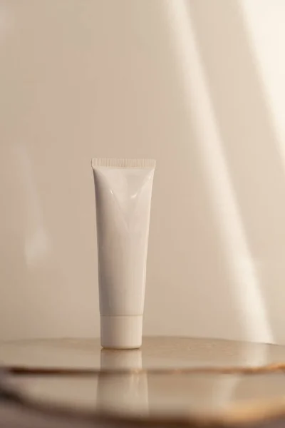 Beyaz Kozmetik Tüp Sıcak Yumuşak Işık Arka Planında Minimalizm Ürünü — Stok fotoğraf