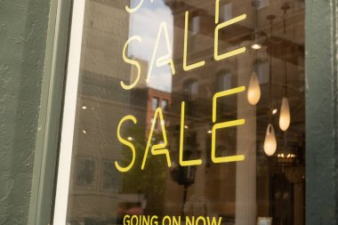 Butik vitrin vitrininde şık bir neon tüp satışı tabelası, sarı renk. Alışveriş, tasarruf konsepti