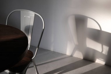 Kahve dükkanında modern gri renkli metal sandalye. Işıklar ve gölgelerle çekilmiş yaratıcı bir iç mekan fotoğrafı. Minimalist konsept, yaşam tarzı, kapat