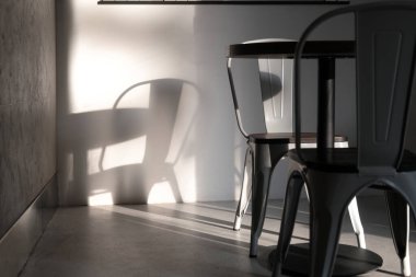 Kahve dükkanında modern gri renkli metal sandalye. Işıklar ve gölgelerle çekilmiş yaratıcı bir iç mekan fotoğrafı. Minimalist konsept, yaşam tarzı, kapat