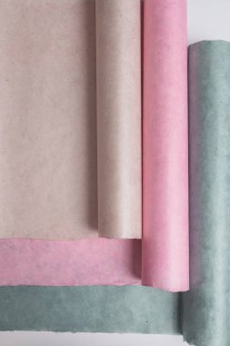 Renkli yumuşak pastel kağıtlar nötr tonlarda yuvarlanır, bej, pembe, yeşil. Metin ve mini görüntüleme için boşluk kopyala