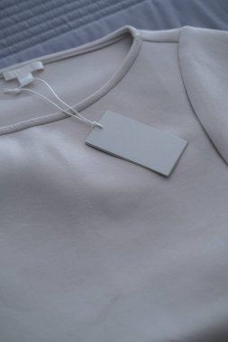 Gri kot kumaşında kıyafet etiketi. Moda markası modeli. Minimalist konsept, minimum ürün natürmort fotoğrafçılık
