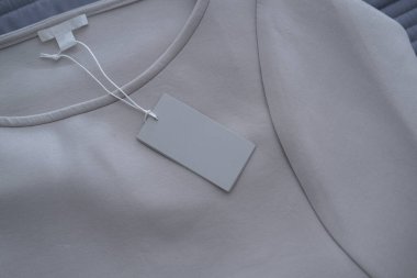 Gri kot kumaşında kıyafet etiketi. Moda markası modeli. Minimalist konsept, minimum ürün natürmort fotoğrafçılık