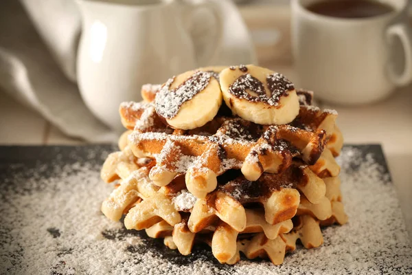 Belgian banana waffles in powdered sugar are on the table