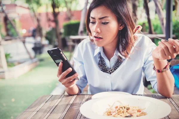 Asian women are happy when eating and playing mobile