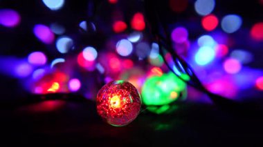 Işıl ışıl parlayan sicim ışıkları kırmızı ve yeşil cam bir topun yer aldığı rüya gibi bir arka plan oluşturuyor..