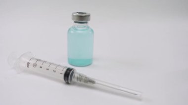 Temiz beyaz bir zemin üzerinde aşı şişesi ve tıbbi şırınga, sağlık, eczane, aşı kampanyaları ve tıbbi stok görüntüleri için ideal.