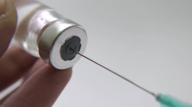 Şırıngayı cam şişeden sıvıyla dolduran ellerin yakın çekimi. Aşı için Enjeksiyon Hazırlanıyor