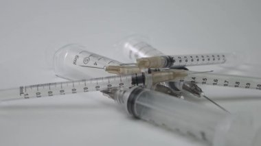 Sivri iğneli pek çok tıbbi plastik şırınga döner döner bir pikabın üzerine istiflenmiş, aşılama, aşılama ve uyuşturucu kullanımı ile ilgili konuları sembolize etmektedir.