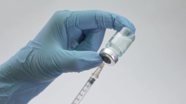 Şırıngaya mavi aşı solüsyonu dolduran eldivenli bir sağlık görevlisinin yakın plan fotoğrafı. Sağlık ve tıbbi kavramlar