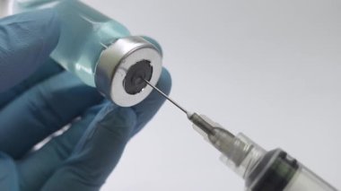 Eldivenli bir doktorun aşı sıvısını cam şişeden şırıngaya çekmesi. Sağlık ve tıbbi kavramlar