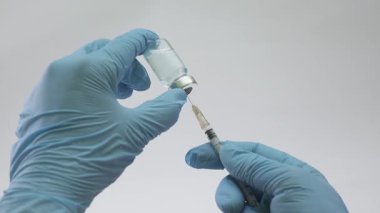 Mavi ilaçları şırınganın içine çeken eldivenli ellerin yakın plan görüntüsü, aşı, klinik tedavi ve modern sağlık uygulamaları için mükemmel..