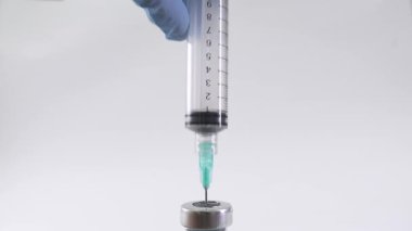 Tıbbi bir şişeden ilaç çekilen bir şırınganın yakın plan çekimi, klinik veya sağlık hizmetleri için ilaç hazırlama sürecini yakalama.