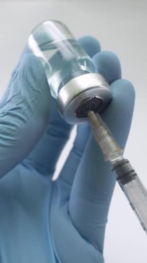 Cam aşı şişesinden sıvı çekerken elinde şırınga tutan tıbbi eldivenler. Sağlık ve tıbbi kavramlar.