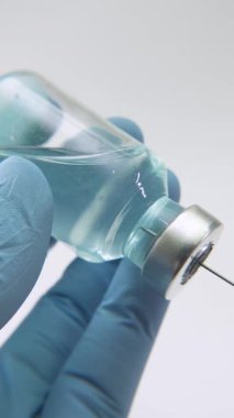 Bir şırıngaya mavi aşı sıvısı çizen, bağışıklık, tıbbi güvenlik ve profesyonel sağlık hizmetlerini temsil eden doktorların aşırı yakın çekimi..