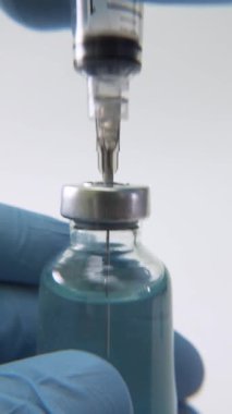 Tıbbi bir şişeden ilaç çekilen bir şırınganın yakın plan çekimi, klinik veya sağlık hizmetleri için ilaç hazırlama sürecini yakalama.