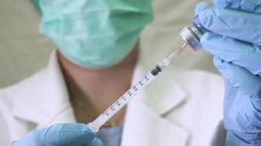 Bir şırıngayı ilaçla dolduran, tıbbi bir prosedürü ve profesyonel sağlık hizmetlerini gösteren eldivenli doktorları kapatın..