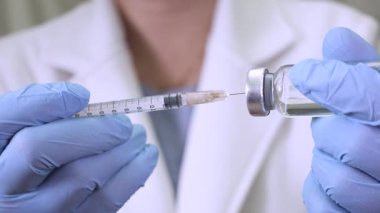 Sağlık uzmanı koruyucu eldiven giyerken şırıngaya yakın çekim tıbbi ayarlarda ilaç dolduruyor.