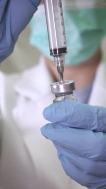 Tıp çalışanları eldiven ile şırıngaya sıvı çekerek profesyonel sağlık hizmetlerini ön plana çıkardılar..