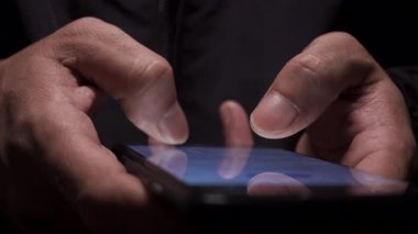 Akşamları akıllı telefon kullanan bir adamın elinin yakın çekimi cep telefonu, dijital iletişim ve modern gece yaşam tarzını temsil ediyor.
