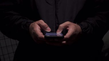 Akıllı telefon kullanan, çevrimiçi etkileşime, ekran zamanına ve günlük mobil teknoloji kullanımına dikkat çeken bir adamın gece yakın çekimi