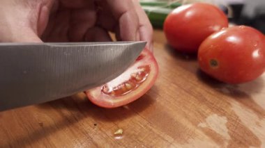 Olgun taze kırmızı domatesleri ince çapraz dilimlemek mutfak bıçağıyla kesme tahtasında taze malzemeler hazırlamak.