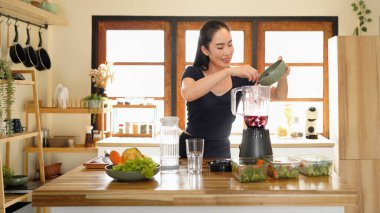 A woman adds fresh blueberries to a blender. Fresh berry smoothie preparation, Woman, hands or blender with blueberries or fruit for smoothie or healthy diet in home..