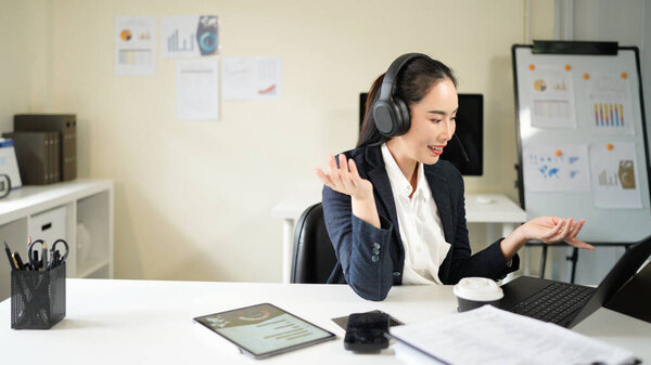 A woman wearing headphones is talking on a laptop.