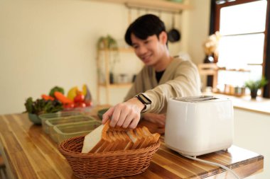 Sandviç dilimleri tutan adam kahvaltıda sandviç yapıyor..