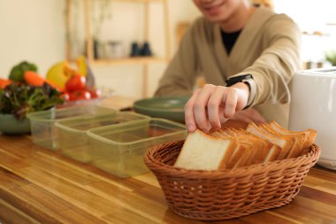 Sandviç dilimleri tutan adam kahvaltıda sandviç yapıyor..
