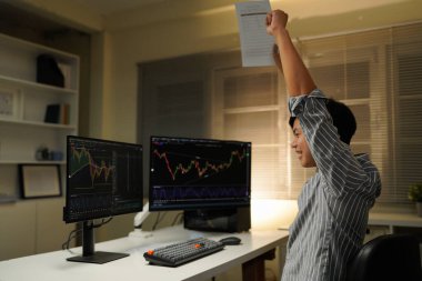 business man congratulations stock trader sitting at a desk in front of computer monitors.