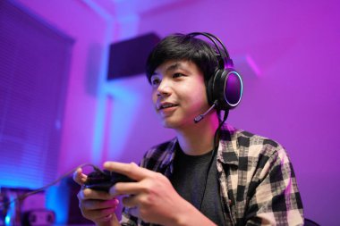 Gamer playing video game wearing headphones in a dark room.