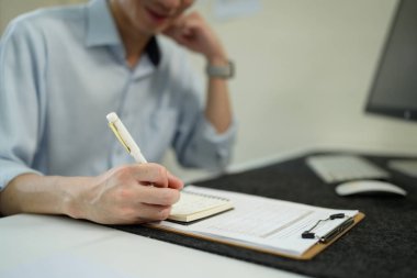 Bir belgedeki verileri (grafikler / grafikler) analiz eden işadamı, kalemle not alıyor. Ofis ayarlama, profesyonel çalışma.