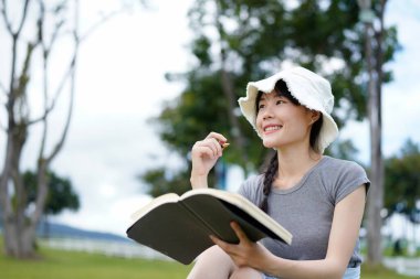 Genç ve çekici Asyalı bir kadının parkta otururken günlüğe yazdığı fotoğraf, bahçede oturan yazar, serbest çalışan kadın, iş ve güzel Asyalı kadınlar hakkında yazılar yazarken rahatlatıcı oluyor..