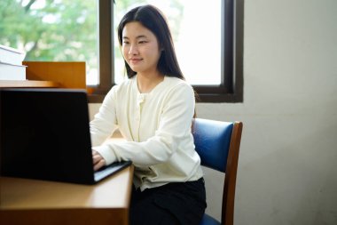 Üniversitede dizüstü bilgisayarla çalışan bir kız..