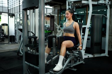 Spor salonunda Inner Thigh Machine 'in bacakları için ağırlık egzersizi yapan kadın...