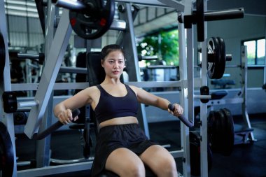 Kadın göğüs presi makinesi üzerinde egzersiz yapıyor. İstemci vücut üzerinde dinamik ve statik yükleri birleştirerek egzersiz yapar...