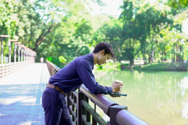 Elinde kahve fincanı olan bir adam ya da bahçede duran yeşil doğa arka planında duran tek kullanımlık kahve ve kitap. Mutlu insanları boş vakitlerinde kabul et ve kahve iç...