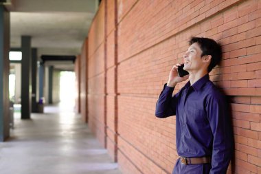 Gülümseyen iş adamı cep telefonuyla dışarıda oturuyor..