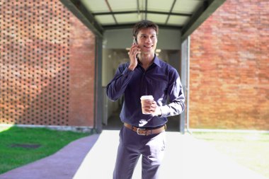 Genç iş adamı kahve molasında dışarıdaki ofis binasından arıyor. Sokaklarda yürüyen bir iş adamı...