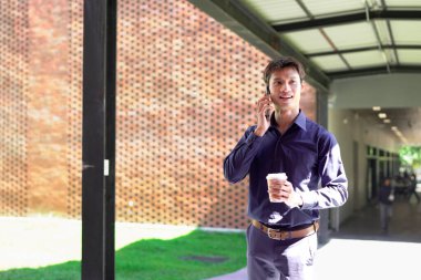 Genç iş adamı kahve molasında dışarıdaki ofis binasından arıyor. Sokaklarda yürüyen bir iş adamı...