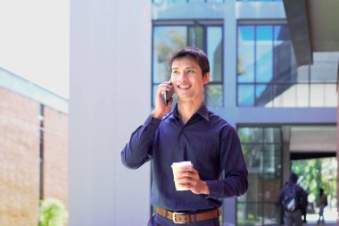 Genç iş adamı kahve molasında dışarıdaki ofis binasından arıyor. Sokaklarda yürüyen bir iş adamı...