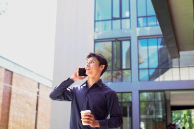 Genç iş adamı kahve molasında dışarıdaki ofis binasından arıyor. Sokaklarda yürüyen bir iş adamı...