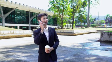 Genç iş adamı kahve molasında dışarıdaki ofis binasından arıyor. Sokaklarda yürüyen bir iş adamı...